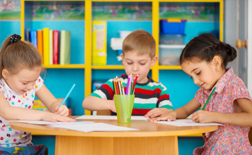 Children using colored pencils on desk