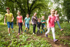 Group of happy children running across the lawn in summer