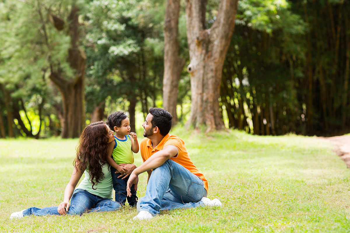A family with a mother, father, and a small boy sitting together outside.