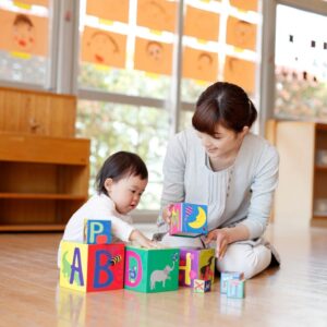 An infant in a daycare room, playing with blocks.